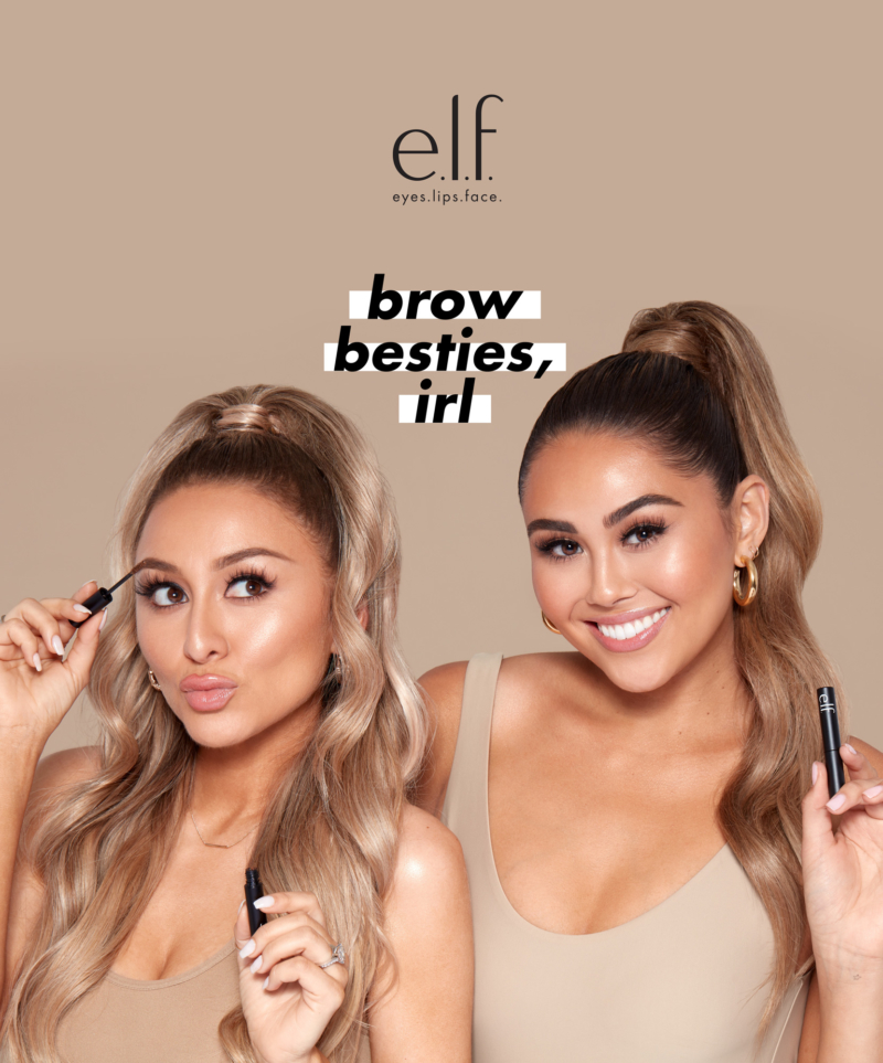 Two smiling people wearing makeup with long ponytails and matching tan tank tops holding eyebrow makeup products from e.l.f. The e.l.f. logo appears in the left corner and the words 