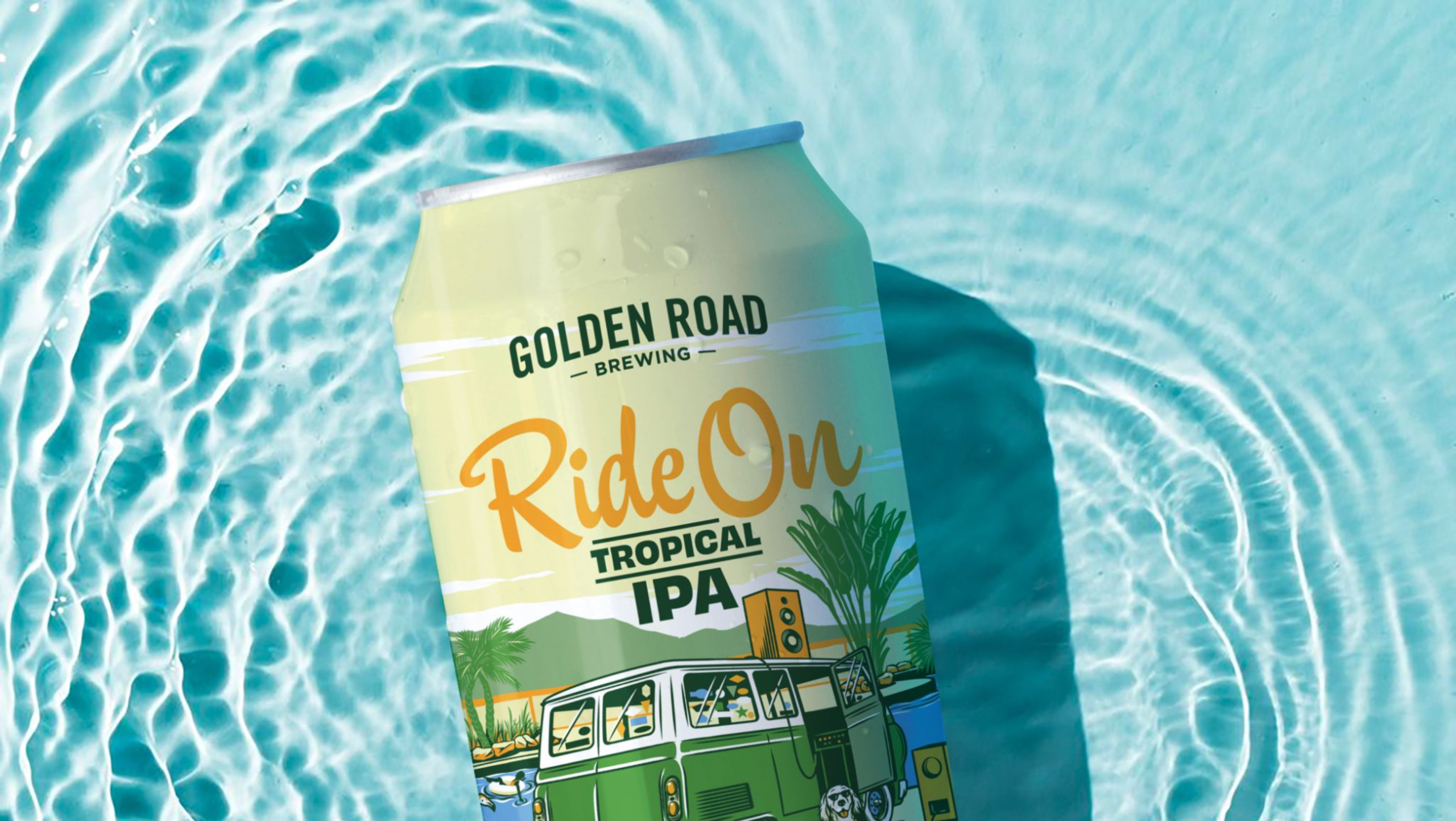 A Golden Road beer can lays in a pool of water. The can is greenish yellow with an illustration of a vintage green van parked next to a pool. The van has vintage speakers attached to its radio. A dog sits next to the van, implausibly wearing sunglasses and a Hawaiian shirt. The beer name 