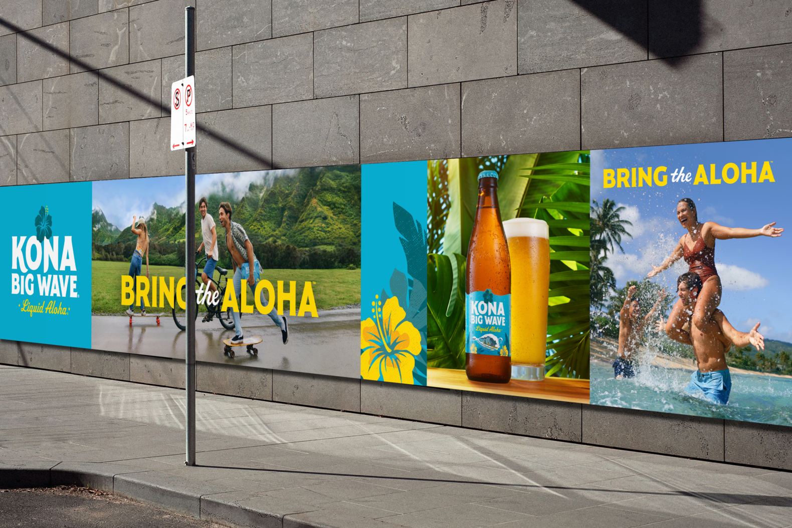 A series of posters from the campaign at street level in an urban setting. From left: the Kona Big Wave logo locked up with “Liquid Aloha” and a blue hibiscus illustration, a photograph of three friends longboarding and biking down a road in Hawaii with green volcanic mountains in the background and the brand tagline, “Bring the Aloha” centered over the photo in yellow and white type, a photo of a bottle of Kona Big Wave next to an ice-cold pint glass full of golden beer with Hawaiian foliage in the background, and a photo of three friends having fun and splashing in the ocean.